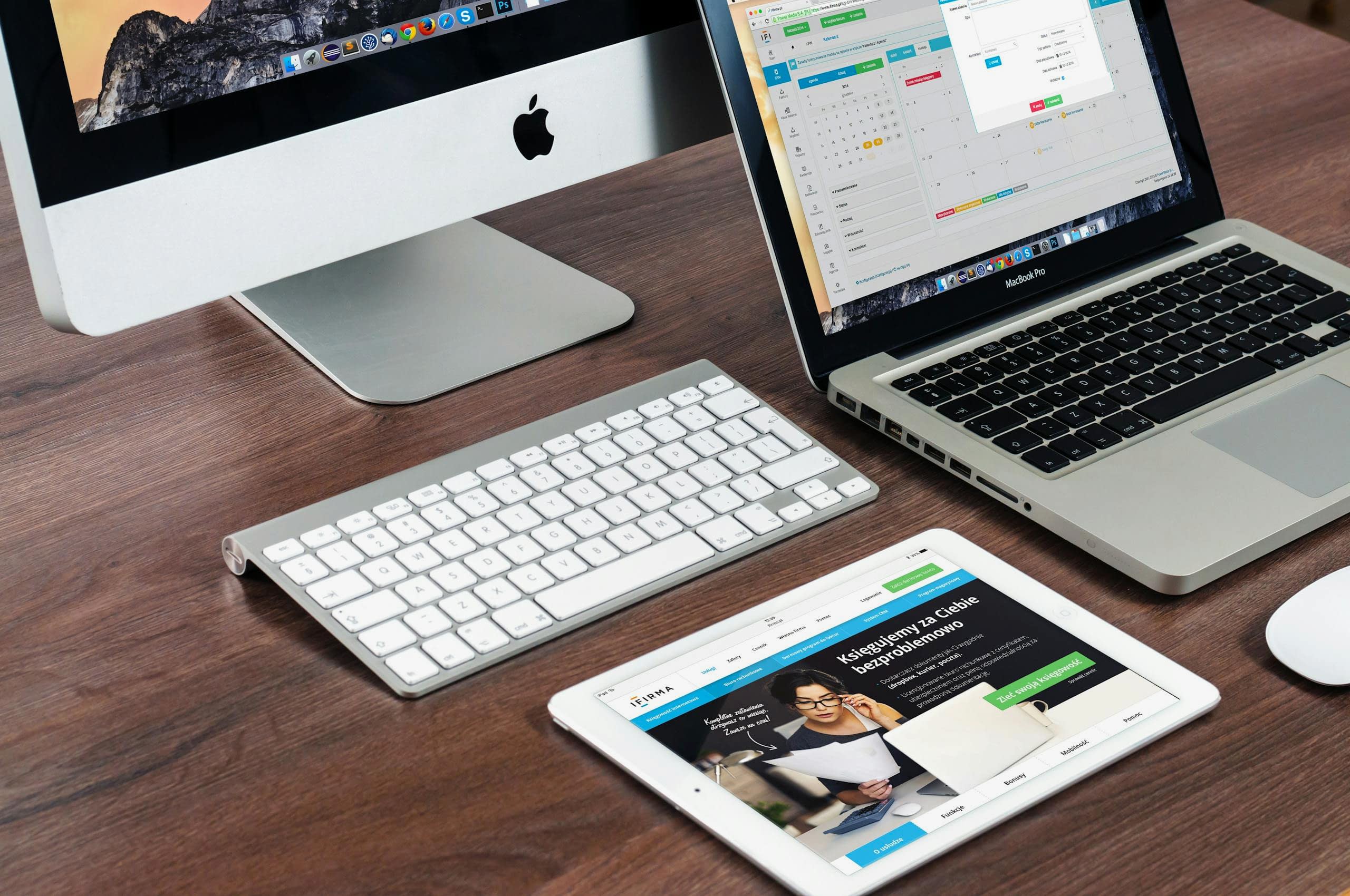 A sleek office desk setup featuring Apple devices: iMac, MacBook, and iPad. Bakı web tasarım ajansı