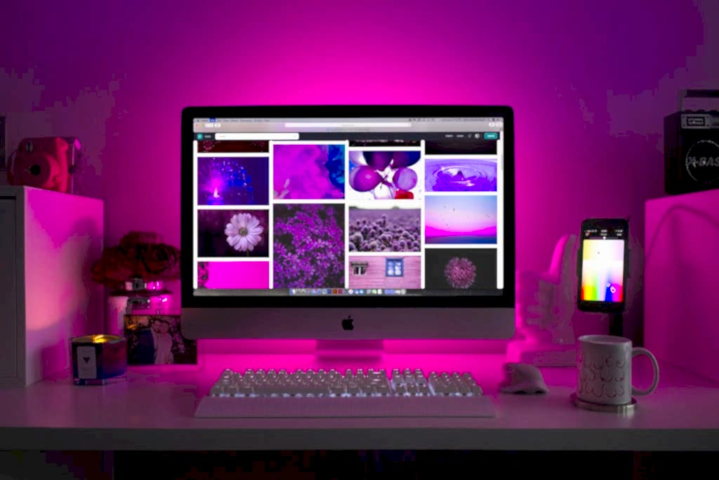 Modern desk setup with neon lighting and a desktop computer displaying colorful images. Bakı en iyi web tasarim ajansi