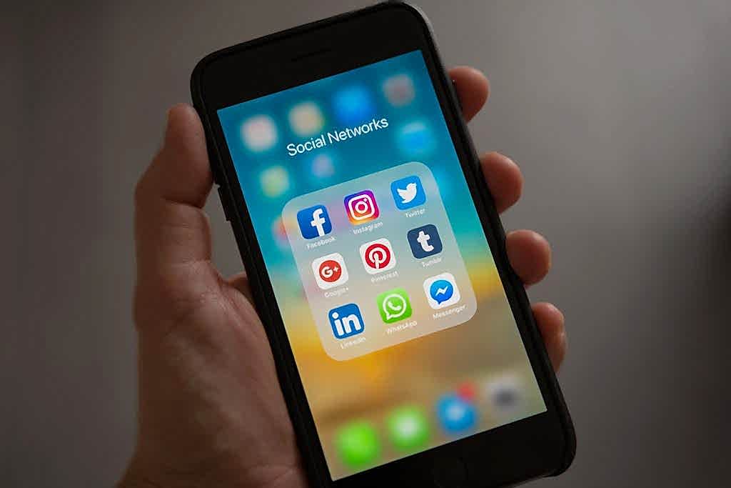 A smartphone displaying various social media icons held in a hand, showcasing modern communication apps. Bakı kurumsal instagram hesap ve reklam yönetimi